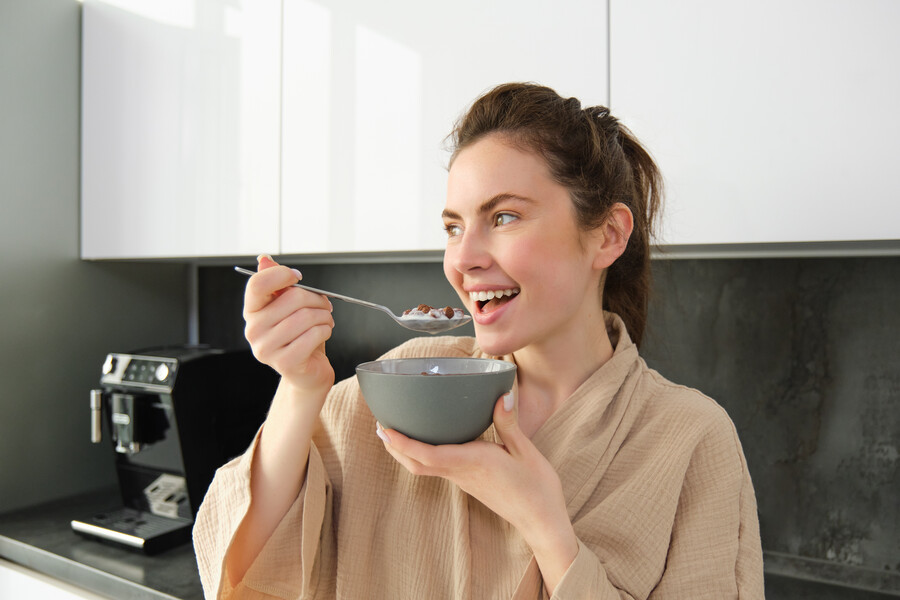 gorgeous-girl-holds-spoon-near-mouth-eats-cereals-with-milk-leans-kitchen-worktop_6d165.jpg