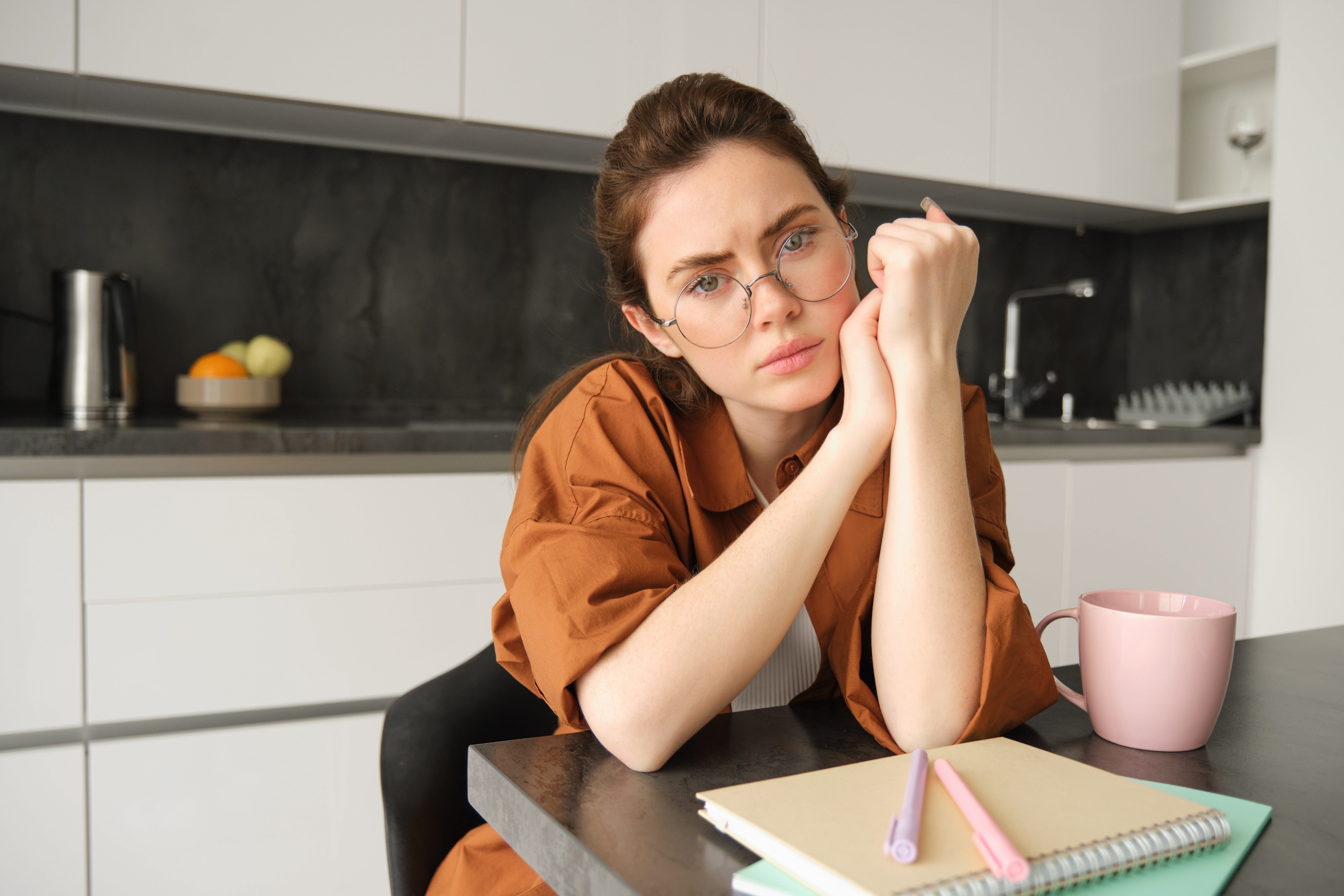 portrait sad tired young woman glasses sitting kitchen home looking upset c48f9