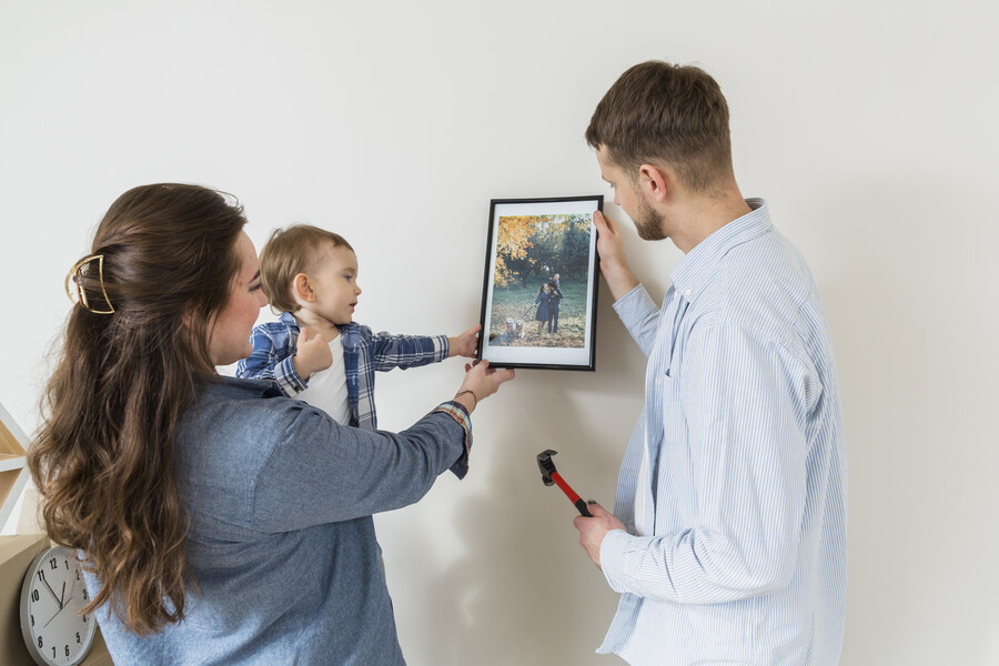 close-up-happy-family-holding-picture-frame-against-wall-new-home_448c4.jpg