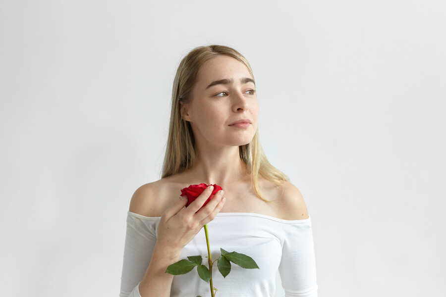 romantic-young-caucasian-female-wearing-open-shoulders-long-sleeved-dress-holding-one-red-rose-from-guy-first-date-looking-sideways-with-dreamy-mysterious-smile-love-passion-romance_7a548.jpg