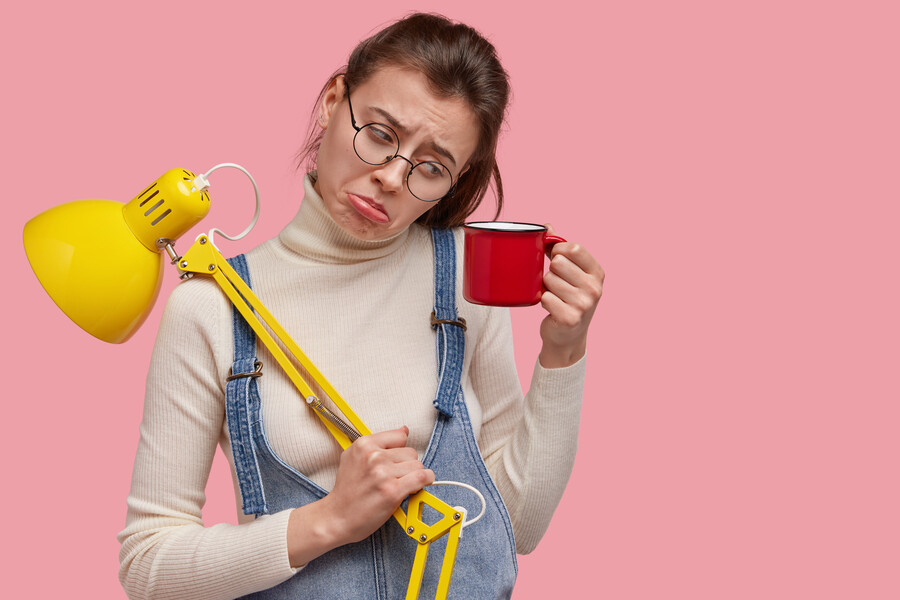 photo-dejected-young-woman-looks-displeasure-mug-drink-holds-yellow-desk-lamp_86f4c.jpg