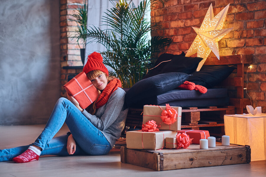 redhead-female-holds-christmas-gift-living-room-with-loft-interior_3dd3e.jpg