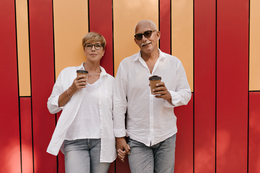 beautiful-woman-with-short-hair-light-clothes-posing-with-cup-coffee-holding-hand-with-grey-haired-man-red-orange_c5830.jpg