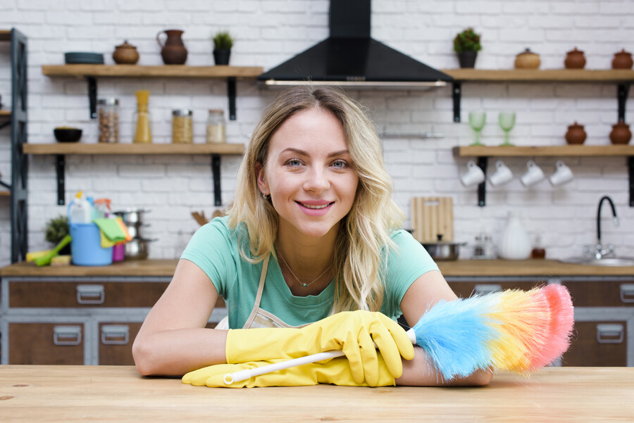 smiling-housekeeper-leaning-kitchen-counter-holding-feather-duster-looking-camera_03898.jpg