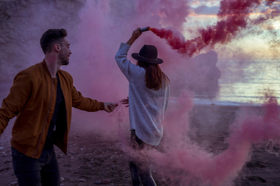 couple-having-fun-with-pink-smoke-bomb-sea-shore_e619e.jpg