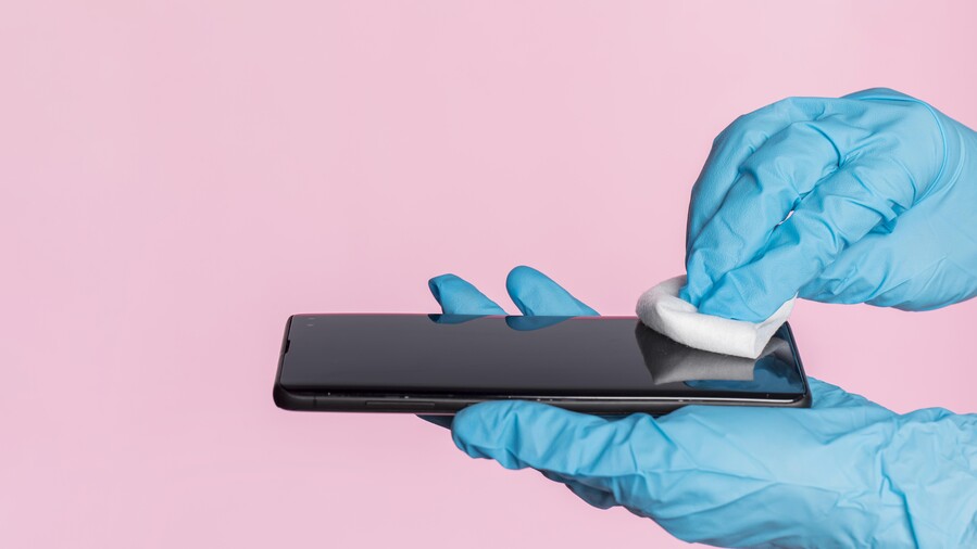 side-view-hands-with-surgical-gloves-disinfecting-smartphone_1f8b7.jpg