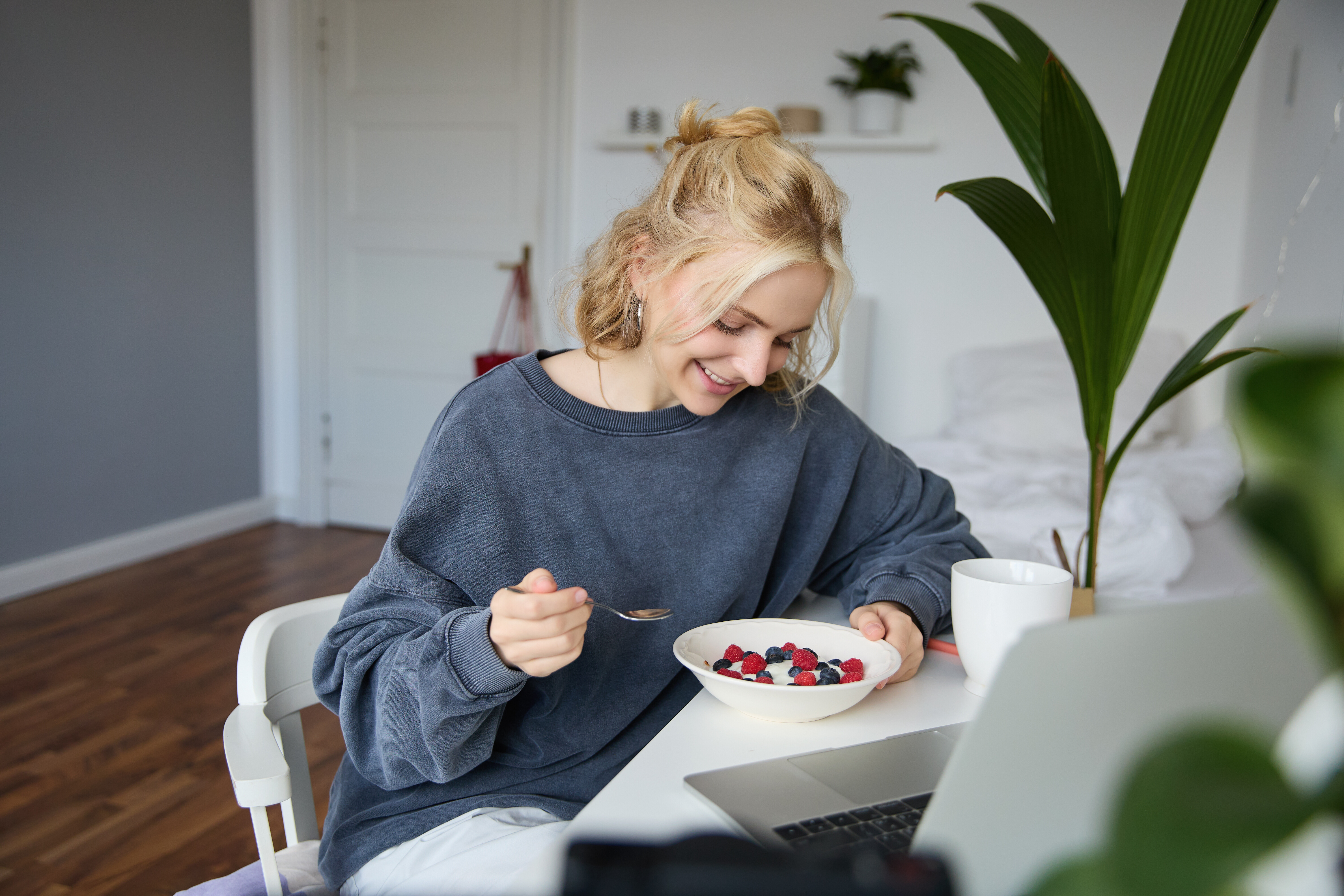 portrait smiling blond young woman eating front laptop watching videos online while having b8c88