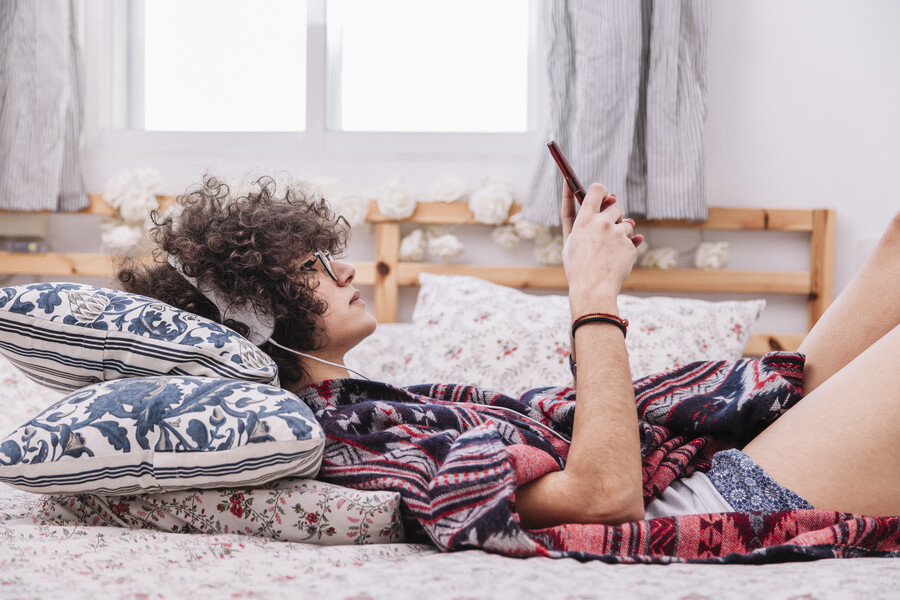 teenager-headphones-using-smartphone-bed_9c451.jpg