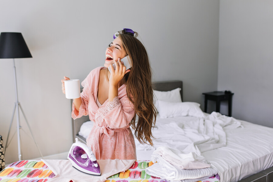 young-housewife-with-long-hair-pink-bathrobe-with-curler-head-home-ironing-clothes-she-speaking-phone-laughing-with-closed-eyes_5f22a.jpg