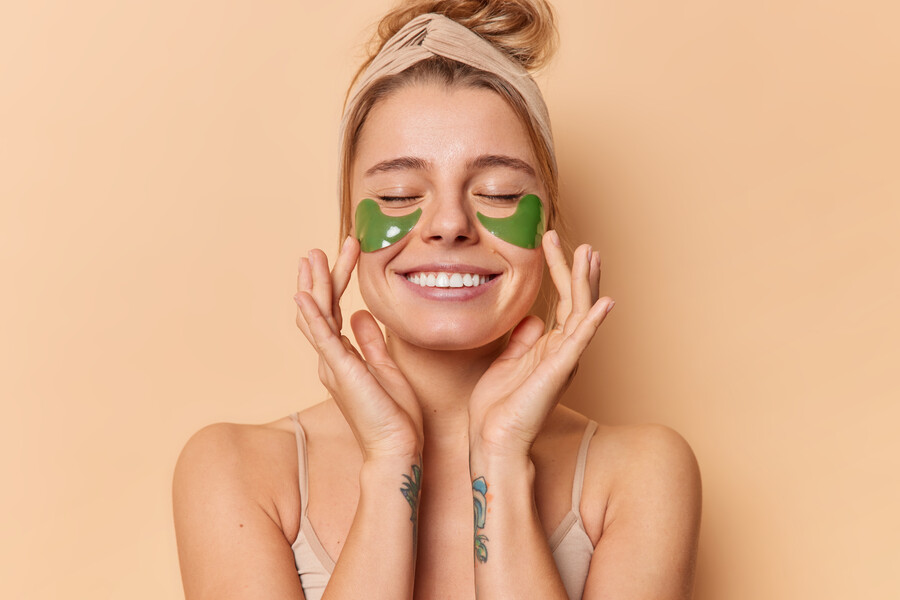 pleased-tender-young-woman-applies-green-hydrogel-patches-eyes-remove-wrinkles-wears-headband-has-healthy-clean-skin-white-even-teeth-isolated-beige-background-wellness-concept_78168.jpg
