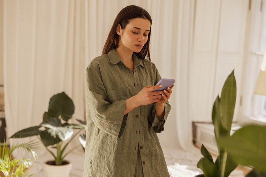 calm-young-caucasian-woman-looks-screen-mobile-phone-her-hands-indoors-brunette-long-green-shirt-reads-sms-social-network-technological-device-concept_3de799095646e970.jpg
